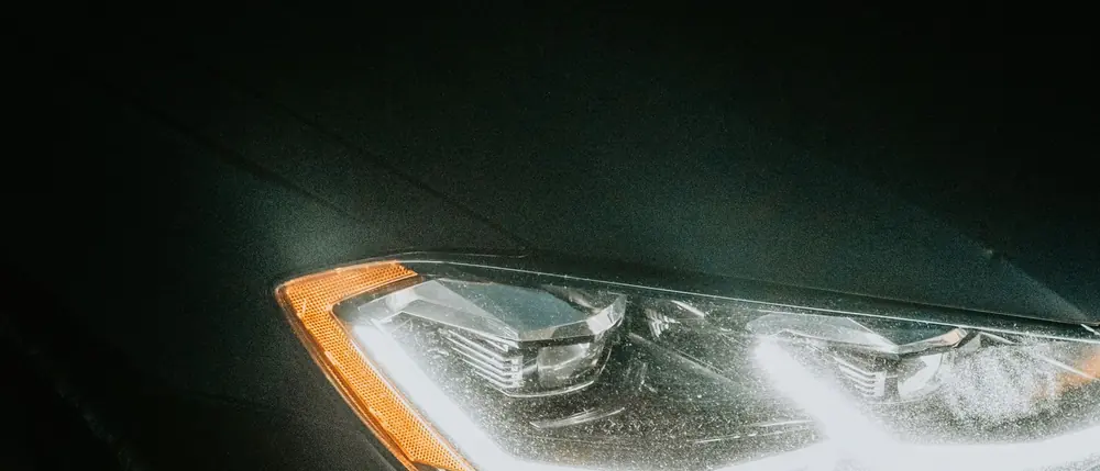Scheinwerfer eines Fahrzeugs, der aus dem Dunkeln auftaucht