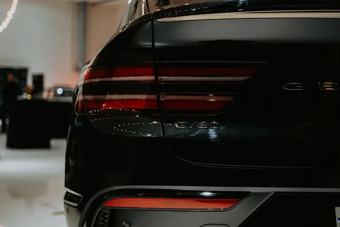 Heckleuchte einer dunklen Limousine im ausgeleuchteten Showroom